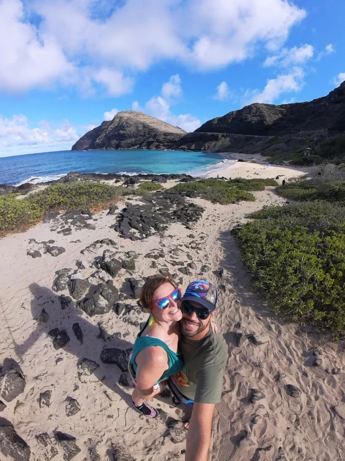 Us posing in front of the ocean in Hawaii with waves and coastline in the background