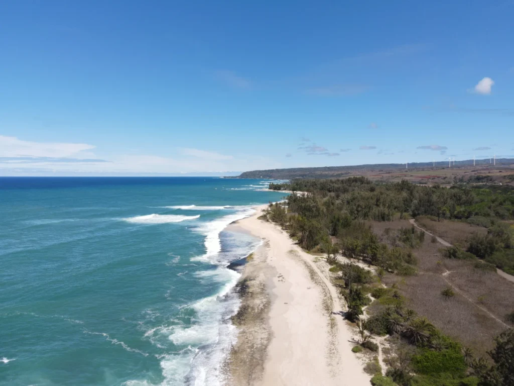 Aerial view of Haleʻiwa Beach in Hawaii with golden sand, turquoise water, and surfers