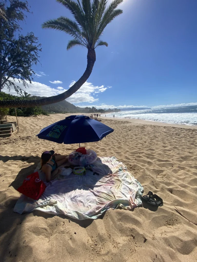 Us relaxing on Sunset Point Beach Park in Hawaii with the sun setting over the ocean