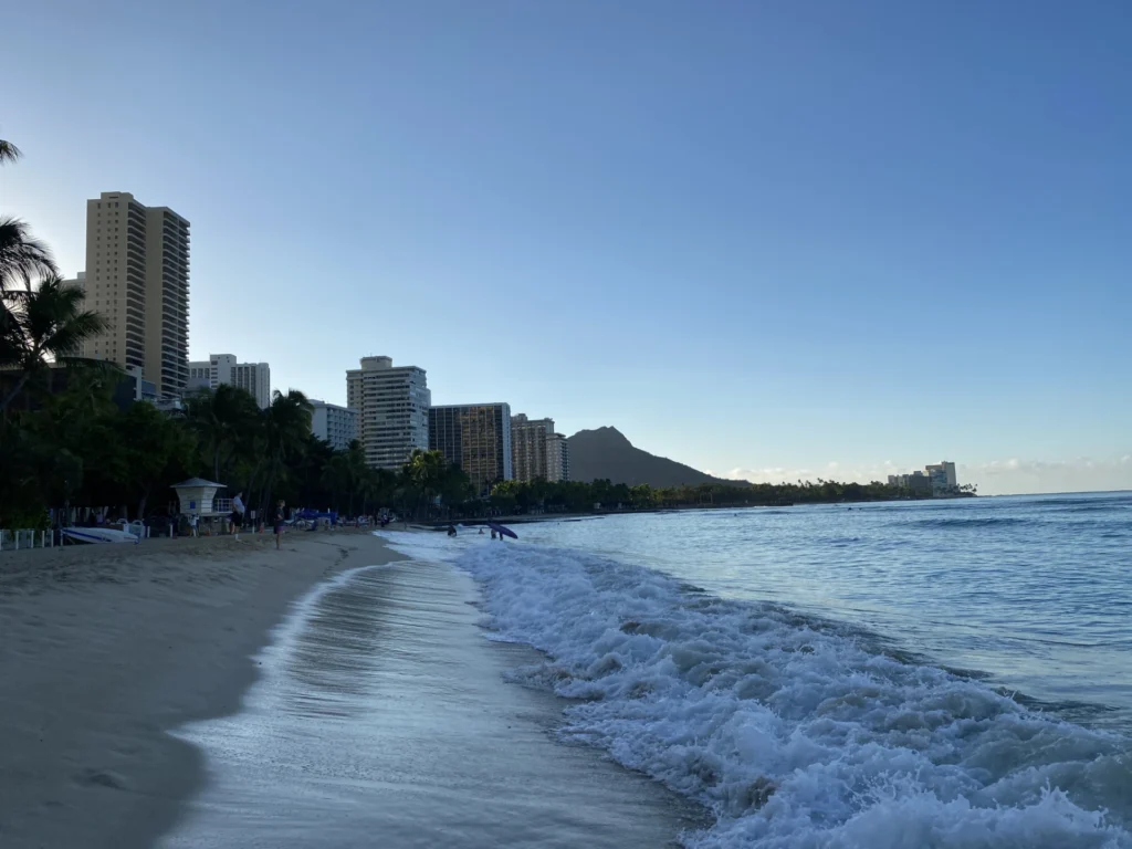 Early morning on Waikiki Beach in Honolulu with calm ocean, soft light, and quiet shoreline