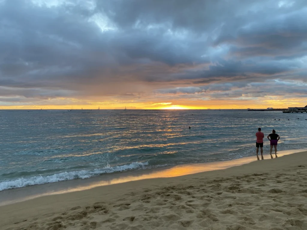Sunset over Kahanamoku Beach in Waikiki with calm water and warm evening colors