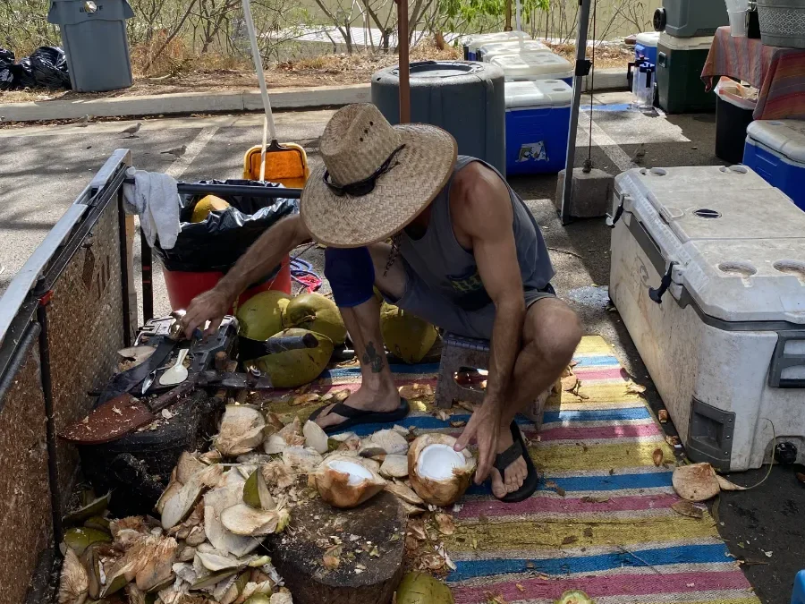 Man chopping fresh coconut at a farmers market in Honolulu